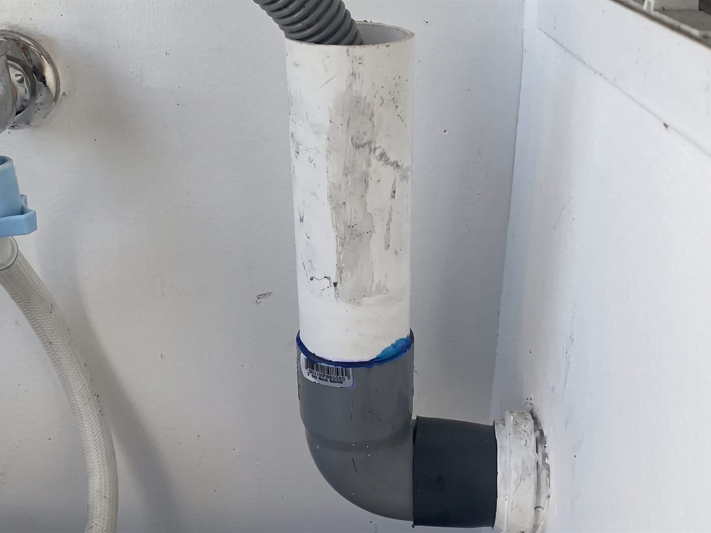 Desagüe de la lavadora en la logia, con la manguera dentro del tubo de PVC y el codo que entra al muro