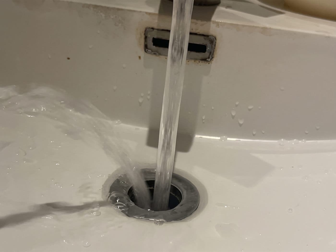 Agua de la llave bajando por el desagüe de un lavamanos de cubierta, después del destape
