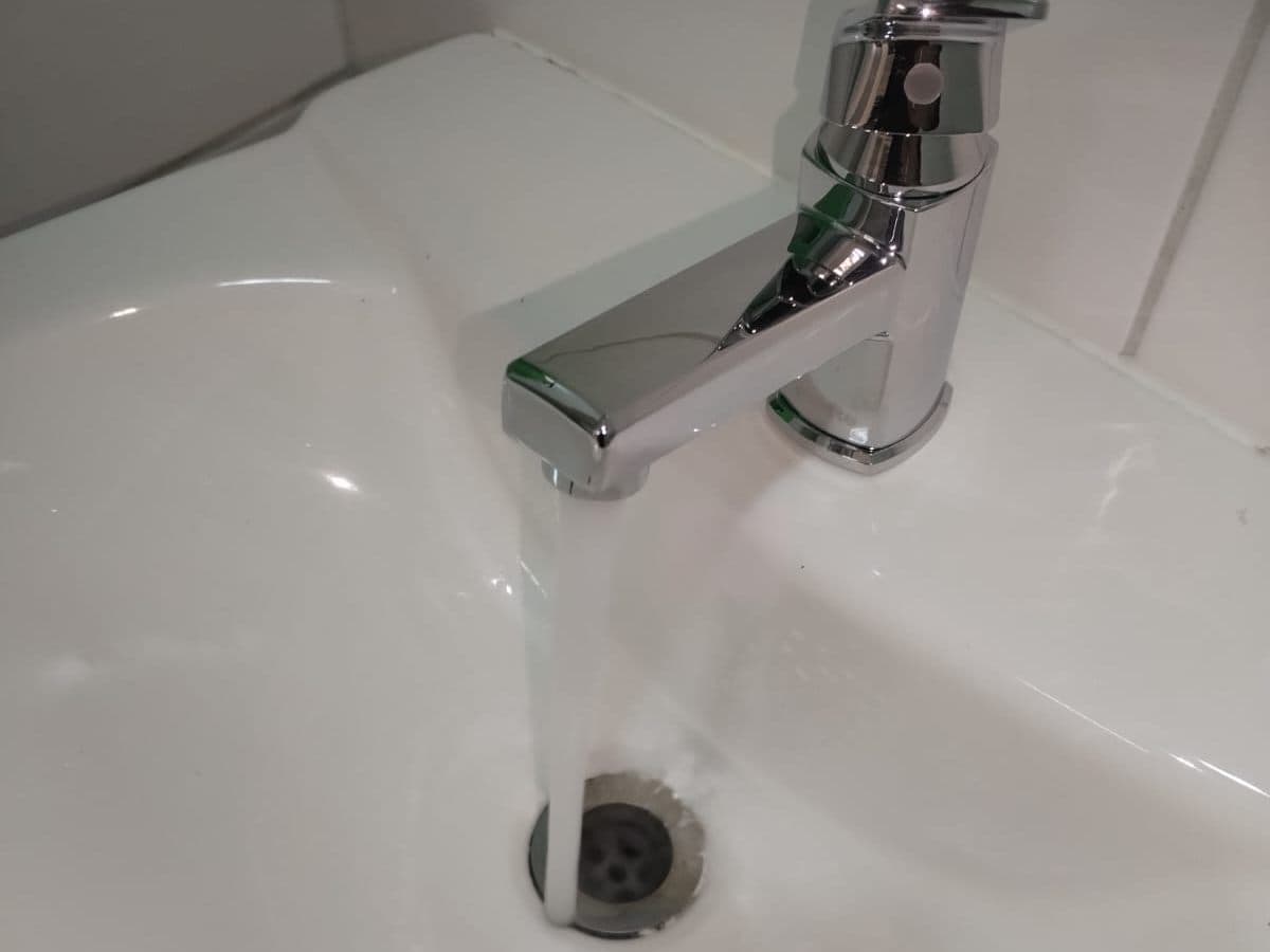 Agua de la llave bajando por el desagüe de un lavamanos después del destape