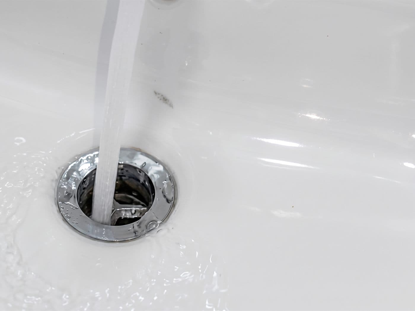 Chorro de agua cayendo directo por el desagüe de un lavamanos, en la prueba después del destape