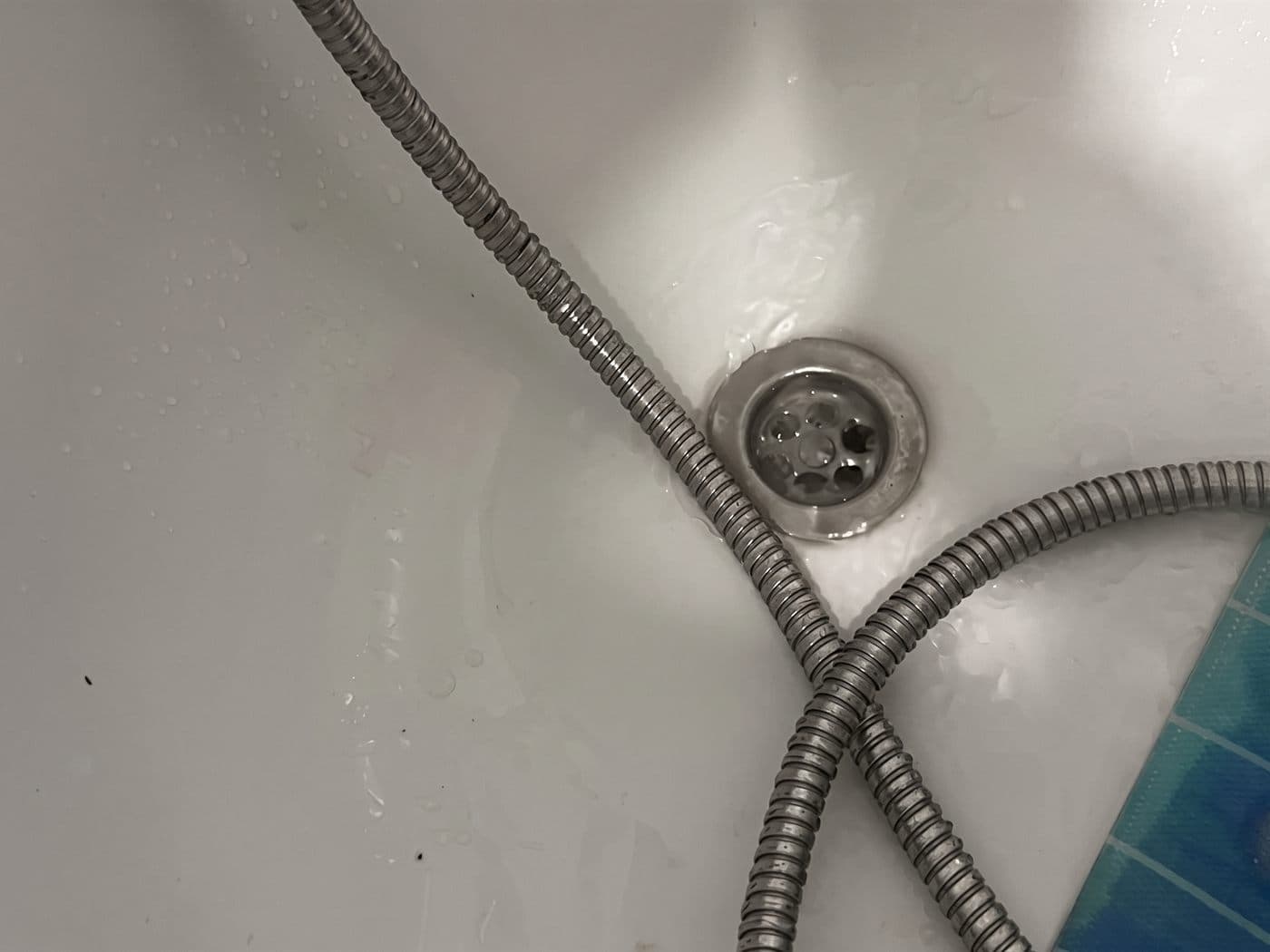 Desagüe de una tina, con la manguera de la ducha cruzada encima